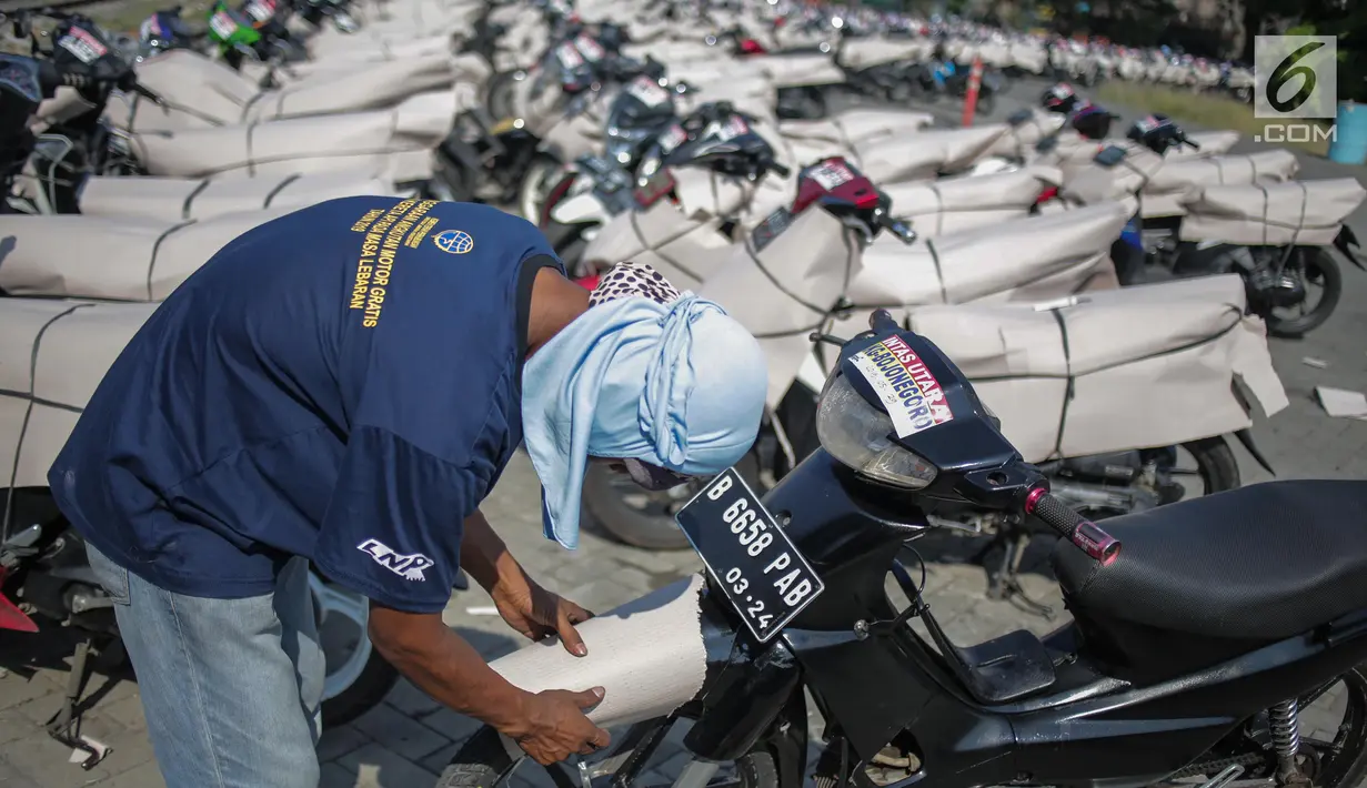 Pekerja membungkus motor pemudik sebelum dikirim dengan kereta api di Stasiun Jakarta Gudang, Selasa (28/5/2019). Direktorat Lalu Lintas dan Angkutan Kereta Api Kementerian Perhubungan mengangkut 18.096 motor pemudik secara gratis pada mudik Lebaran 2019. (Liputan6.com/Faizal Fanani)