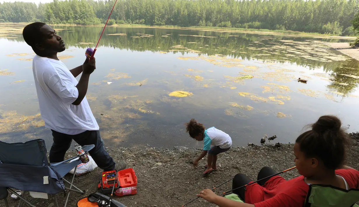 Keluarga saat memancing di sepanjang pantai tepi Danau Cheney di Anchorage, Alaska (5/7/2019). Suhu pada hari Kamis, 4 Juli, mencapai 90 derajat untuk pertama kalinya di Anchorage dan cuaca panas diperkirakan akan berlanjut hingga minggu depan. (AP Photo/Anne Raup)