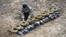 Seorang pencari ranjau Kementerian Dalam Negeri menyiapkan bahan peledak pada sebuah lubang untuk meledakkannya dekat ladang ranjau setelah pertempuran baru-baru ini di Desa Moshchun, dekat Kyiv, Ukraina, 19 April 2022. (AP Photo/Efrem Lukatsky)