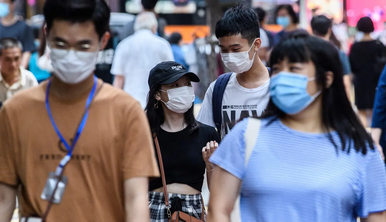 Pejalan kaki mengenakan masker sebagai tindakan pencegahan Covid-19 saat berjalan di Hong Kong (13/5/2020). Dua orang di Hong Kong dinyatakan positif Covid-19, mengakhiri perjalanan 24 hari tanpa kasus baru yang mulai melonggarkan peraturan jarak sosial. (AFP/Anthony Wallace)