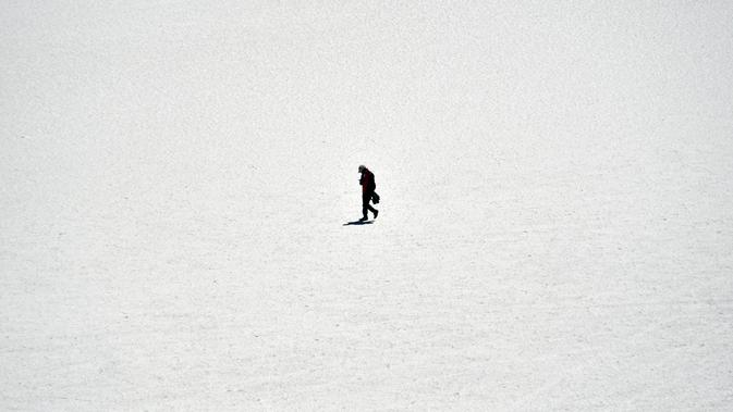 Seorang pria berjalan di Salar de Uyuni, dataran garam terluas di dunia yang terletak di Altiplano, barat daya Bolivia, 28 September 2019. Permukaan Salar de Uyuni tertutup lapisan garam setinggi beberapa kaki, menjadikan dataran ini tetap kering sepanjang tahun. (Photo by Aizar RALDES / AFP)