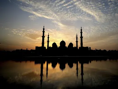 Matahari terbenam di belakang Masjid Agung Sheikh Zayed di Abu Dhabi, Uni Emirat Arab (8/11/2019). Masjid ini adalah masjid terbesar ketiga di dunia setelah masjid di Mekkah dan Madinnah. (AFP Photo/Kamran Jebreili)