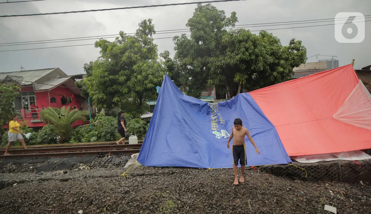 Tenda pengungsi banjir yang didirikan di jalur rel kereta commuterline Tangerang-Duri di Kembangan Baru, Jakarta, Jumat (3/1/2020). Jalur rel yang nonaktif sementara karena banjir dimanfaatkan warga untuk mendirikan tenda darurat karena rumah mereka masih terendam. (Liputan6.com/Faizal Fanani)