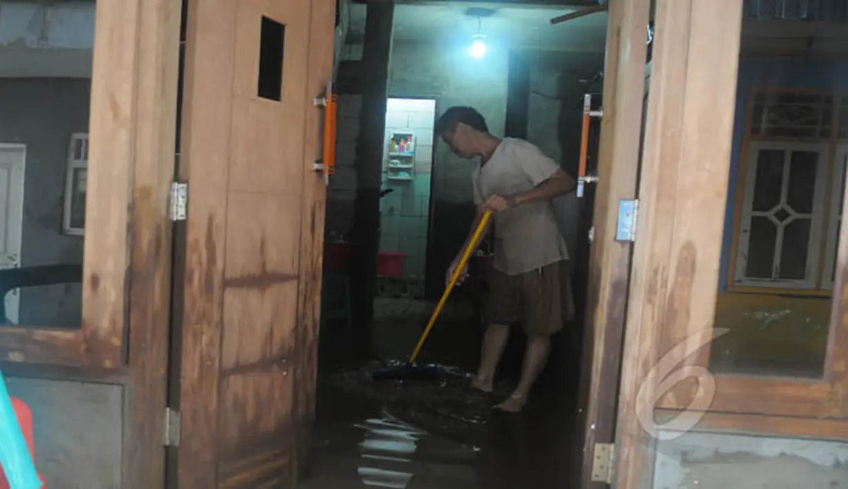 Seorang warga membersihkan rumah dari sisa-sisa genangan air yang merendam pemukiman mereka di kawasan Kampung Pulo, Jatinegara, Jakarta Timur, Selasa (10/2/2015). (Liputan6.com/Herman Zakharia)