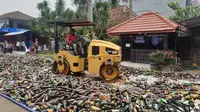 Polres Metro Tangerang Kota menghancurkan ribuan botol minuman keras menggunakan buldozer, Rabu (30/3/2022). (Foto:Liputan6/Pramita Tristiawati)