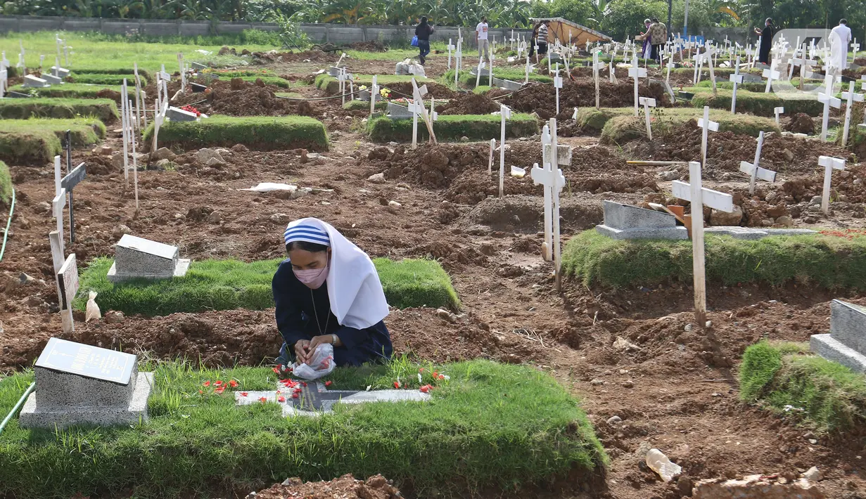 Biarawati berdoa di makam saat misa perayaan ekaristi peringatan arwah bagi korban Covid-19 di area TPU Rorotan, Jakarta Utara, Selasa (30/11/2021). Misa yang dipimpin oleh Uskup Ignatius Kardinal Suharyo tersebut dilakukan untuk mendoakan arwah korban Covid-19. (Liputan6.com/Herman Zakharia)