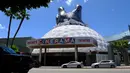 Kendaraan melintasi bioskop Cinerama Dome yang atapnya dihiasi godzilla raksasa di Hollywood, California, AS pada 20 Mei 2019. Hinggapnya godzilla raksasa untuk menyambut sekuel Godzilla: King of the Monsters yang akan dirilis pada 31 Mei 2019. (Photo by Chris Delmas / AFP)