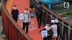 Sejumlah aktivis yang tergabung dalam Extintion Rebellion (XR) dan Walhi Jakarta melakukan aksi di JPO Pinisi, Jalan Jenderal Sudirman, Jakarta, Senin (14/11/2022). Aksi tersebut dilakukan untuk menyerukan kepada para pemimpin agar menghentikan “pencucian hijau” dan praktik ekonomi “business-as-usual” yang secara sistematis memperburuk krisis iklim dan mendorong umat manusia pada kehancuran ekologis & kepunahan massal. Negara-negara G20 turut menyumbang atas 80 persen emisi karbon dunia dan 60 persen populasi penduduk bumi. (Liputan6.com/Angga Yuniar)