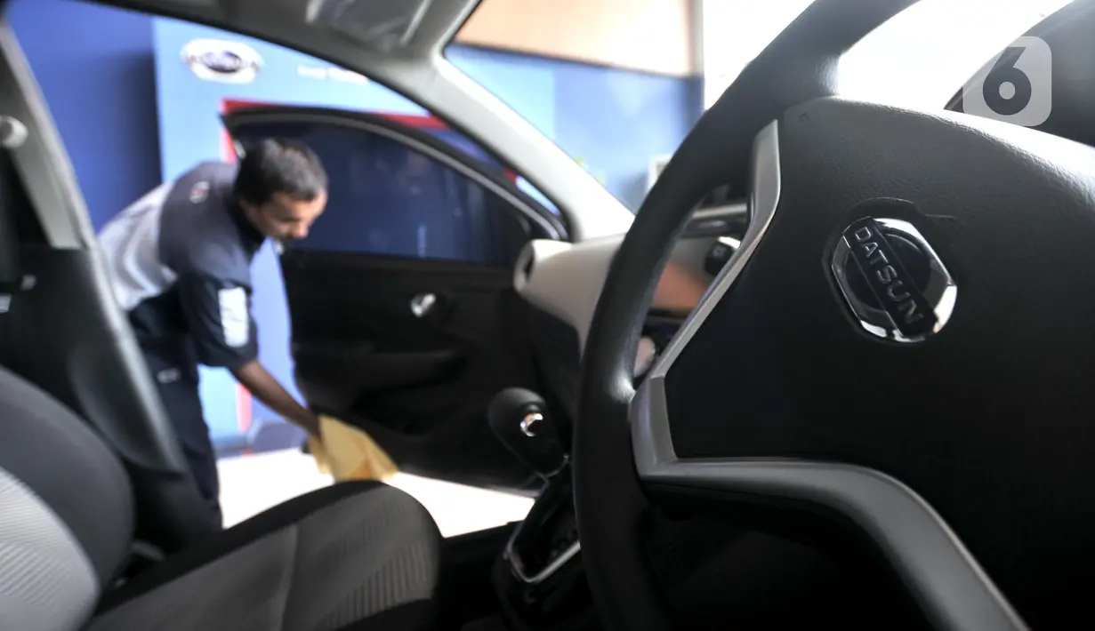 Pekerja membersihkan mobil Datsun Go+ Panca di Diler Nissan kawasan Pulogadung, Jakarta, Rabu (27/11/2019). Pabrik mobil Datsun akan dialihfungsikan untuk memproduksi mesin mobil jenis lain dan lebih fokus mengembangkan kendaraan listrik. (merdeka.com/Iqbal Nugroho)