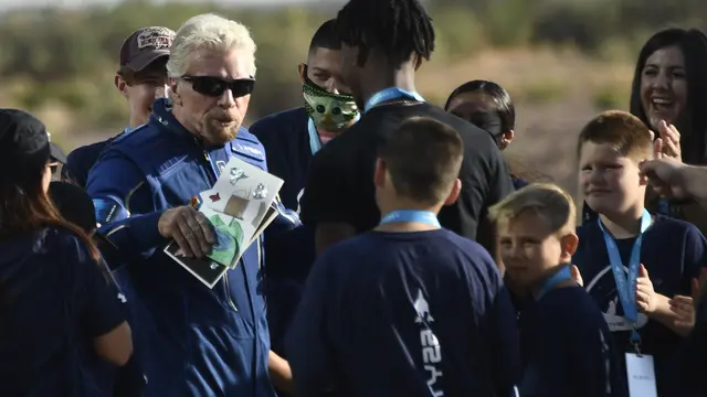 Richard Branson menerima beberapa kartu dari anak-anak saat dia berjalan keluar dari Spaceport America, dekat Truth and Consequences, New Mexico pada 11 Juli 2021 sebelum melakukan perjalanan ke luar angkasa. Patrick T. FALLON / AFP