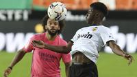 Gelandang Valencia, Yunus Musah berebut bola dengan bek Real Madrid, Marcelo berebut bola pada lanjutan La Liga di Stadion Mestalla, Selasa (9/11/2020) dinihari WIB. Real Madrid kalah telak 1-4 dari tuan rumah Valencia. (AP Photo/Alberto Saiz)