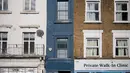 Seorang pejalan kaki melewati bagian depan bangunan yang dijuluki "Rumah Tersempit di London" (cat biru) di London barat pada 5 Februari 2021. Rumah unik yang terdiri dari lima tingkat tersebut dibanderol dengan harga mencapai £ 990.000 atau senilai dengan Rp 19,4 miliar. (Tolga Akmen/AFP)