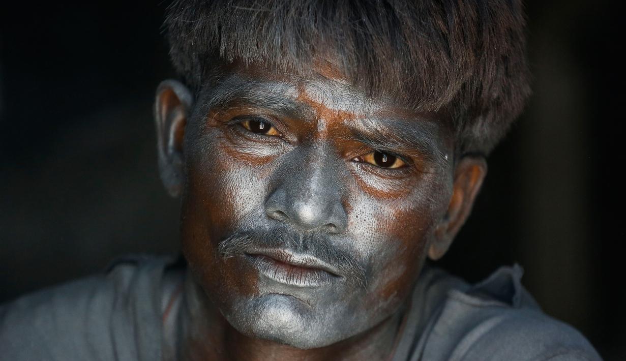 Wajah seorang pekerja dipenuhi bubuk mesiu untuk membuat petasan, di sebuah pabrik pinggiran  Ahmadabad, Senin (22/10). Permintaan petasan di India semakin meningkat jelang perayaan Festival "Cahaya" Diwali bagi umat Hindu. (AP/Ajit Solanki)