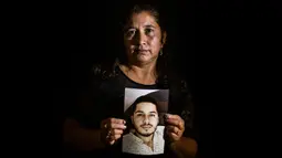 Gladys Betancourth, 51, ibu dari Oscar Obando, 24, satu dari 8 pemuda yang dibunuh dalam pesta di pinggiran Samaniego, Kolombia pada 16 Agustus, berpose dengan foto putranya pada 2 September 2020. Pembunuhan kembali berdarah di pedesaan Kolombia. Korbannya kebanyakan masih muda. (Luis ROBAYO/AFP)