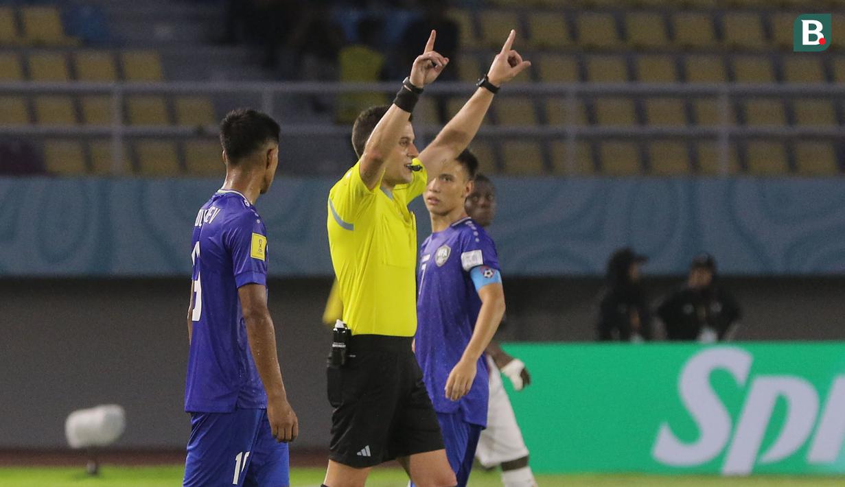 <p>Wasit Gustavo Tejera asal Uruguay memberikan isyarat setelah memeriksa VAR (Video assistant Referee) yang berpotensi terjadinya tendangan penalti dalam pertandingan Timnas Mali U-17 melawan Uzbekistan U-17 dalam babak penyisihan Grup B Piala Dunia U-17 2023 di Stadion Manahan, Solo, Jumat (10/11/2023). VAR baru pertama kali diterapkan dalam sebuah turnamen resmi di Indonesia. (Bola.com/Arief Bagus)</p>