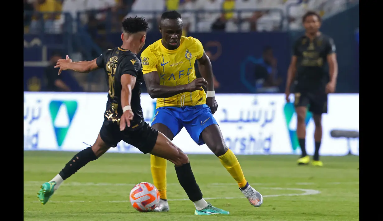 Pemain Al Nassr, Sadio Mane (kanan), berusaha melewati hadangan pemain Al Taawon dalam laga pekan ke-2 Liga Arab Saudi 2023/2024 yang berlangsung di KSU Football Stadium, Sabtu (19/8/2023) dini hari WIB. (AFP/Fayez Nureldine)