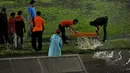 Sejumlah offial pertandingan mencoba menguras air yang menggenangi lapangan Stadion H Agus Salim Padang, Sabtu (17/1/2015) . (Liputan6.com/Johan Tallo)