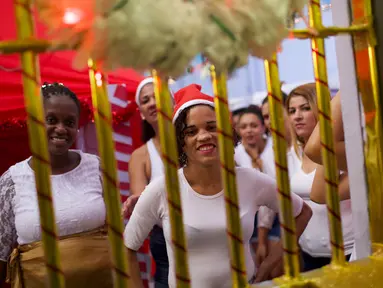Narapidana perempuan tersenyum di balik jeruji penjara yang dihias dengan dekorasi Natal di Penjara Nelson Hungria, Rio de Janeiro, Kamis (13/12). Penjara ini mengadakan kompetisi menghias sel menggunakan dekorasi bernuansa natal. (AP/Silvia Izquierdo)