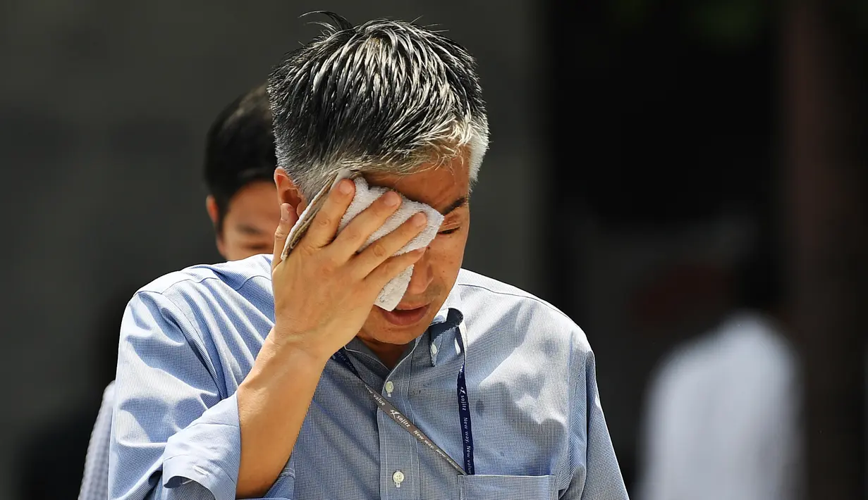 Seorang pria menyeka wajahnya saat berjalan selama gelombang panas melanda Tokyo, Jepang (1/8/2019). Badan Meteorologi Jepang (JMA) mencatat suhu tertinggi Tokyo mencapai 35,4 derajat celcius. (AFP Photo/Charly Triballeau)