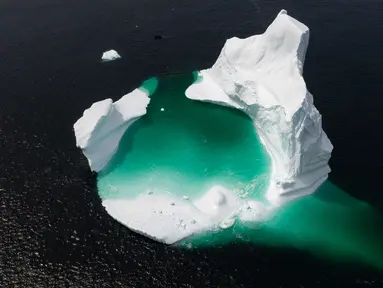 Kapal Kapten Edward Kean melewati gunung es terapung di Teluk Bonavista, Newfoundland, Kanada, 29 Juni 2019. Banyaknya gunung es terapung menjadikan Newfoundland destinasi wisata baru di Kanada. (Johannes Eisele/AFP)