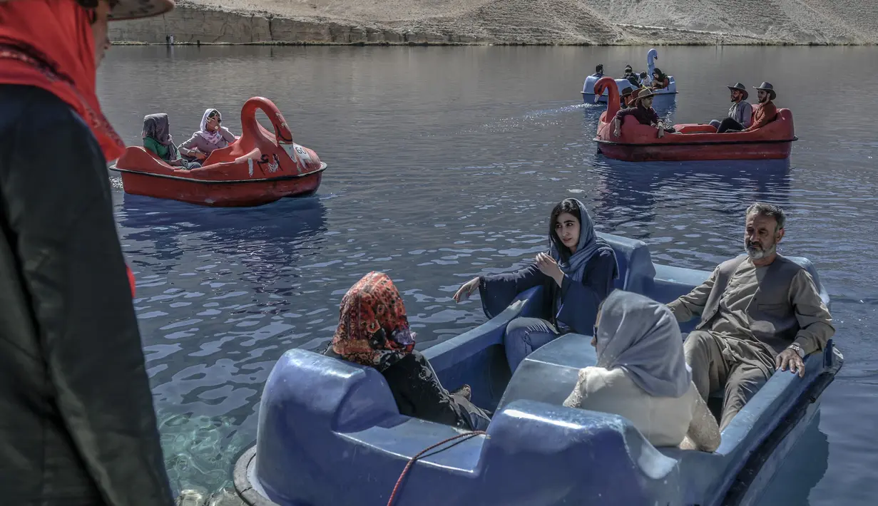 Wisatawan duduk di atas perahu dayung untuk berkendara di Danau Band e-Amir, Provinsi Bamiyan, 4 Oktober 2021. Danau Band-e Amir yang memiliki perairan biru menakjubkan disebut juga sebagai Grand Canyon Afghanistan. (BULENT KILIC/AFP)