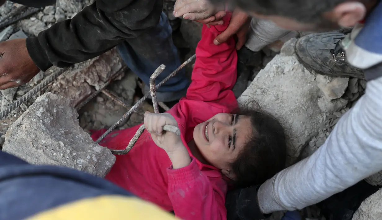 Seorang gadis menangis saat anggota Syrian Civil Defence atau White Helmets berusaha menyelamatkannya dari timbunan puing bangunan usai serangan udara pasukan pemerintah di Desa Tal Mardikh, Provinsi Idlib, Suriah, Kamis (19/12/2019). Pasukan Suriah kian intens menyerang Idlib. (Omar HAJ KADOUR/AFP)
