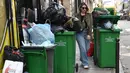 Seorang pejalan kaki berjalan di antara tempat sampah yang penuh di distrik ke-2 Paris saat petugas kebersihan mogok menentang reformasi pensiun, membuat banyak jalan di ibu kota penuh dengan sampah yang berbau busuk, Kamis (17/3/2023). (Photo by Bertrand GUAY / AFP)