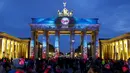 Wisatawan mengamati Gerbang Brandenburg yang dihiasi cahaya saat pembukaan Festival cahaya, Jerman, Sabtu (10/10/2015). Festival ini merupakan event tahunan yang diadakan setiap bulan Oktober selama dua belas hari.(REUTERS/Hannibal Hanschke)