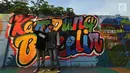 Para remaja berswafoto dengan latar gambar mural/grafiti yang ada di Kampung Bekelir, Jalan Perintis Kemerdekaan, Kota Tangerang, Banten, Selasa (17/4). Jumlah mural/grafiti di kampung ini sekarang mencapai 1.121 gambar. (Merdeka.com/Arie Basuki)