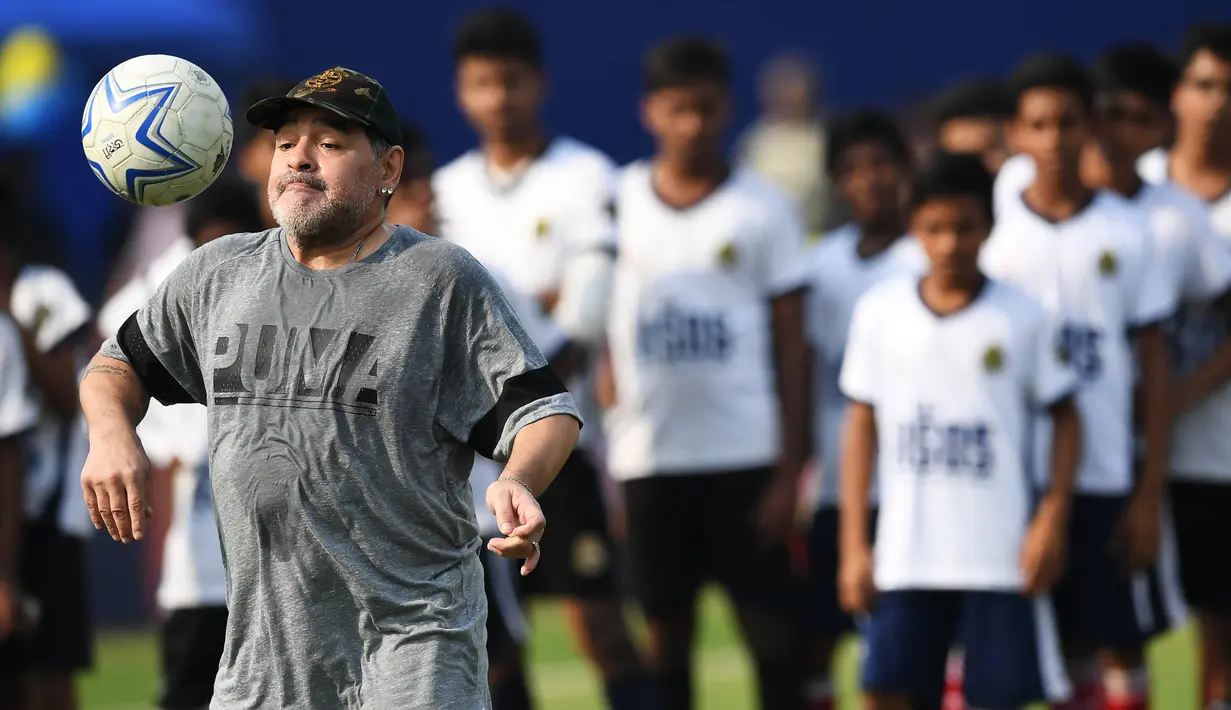 Legenda sepak bola, Diego Maradona, melakukan juggling saat memberikan pelatihan kepada anak-anak di Barasat, Selasa (12/12/2017). Kunjungan ini dilakukan pria asal Argentina itu dalam rangkaian liburan. (AFP/Dibyangshu Sarkar)