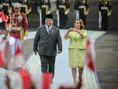 Presiden Republik Indonesia Prabowo Subianto (kiri) bersam Presiden Peru Dina Boluarte menyaksikan anak-anak mengibarkan bendera kedua negara sebelum pertemuan mereka di Istana Merdeka, Jakarta, pada 11 Agustus 2025. (Bay ISMOYO/AFP)