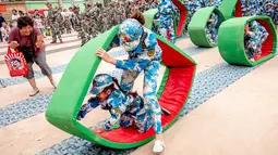 Sejumlah anak-anak melakukan simulasi latihan militer di sebuah taman kanak-kanak di provinsi Henan, China (30/5). Latihan militer ini dilakukan untuk menjelang Hari Anak Internasional yang jatuh pada 1 Juni. (AFP)