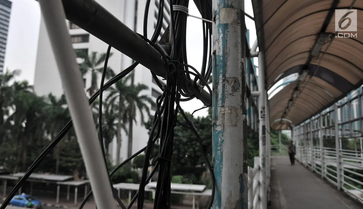 Jembatan penyeberangan orang (JPO) yang berada di Jalan Sudirman, Jakarta, Rabu (17/4). Kabel-kabel listrik yang tidak tertata rapi sangat membahayakan pejalan kaki yang melintas. (Merdeka.com/Iqbal Nugroho)