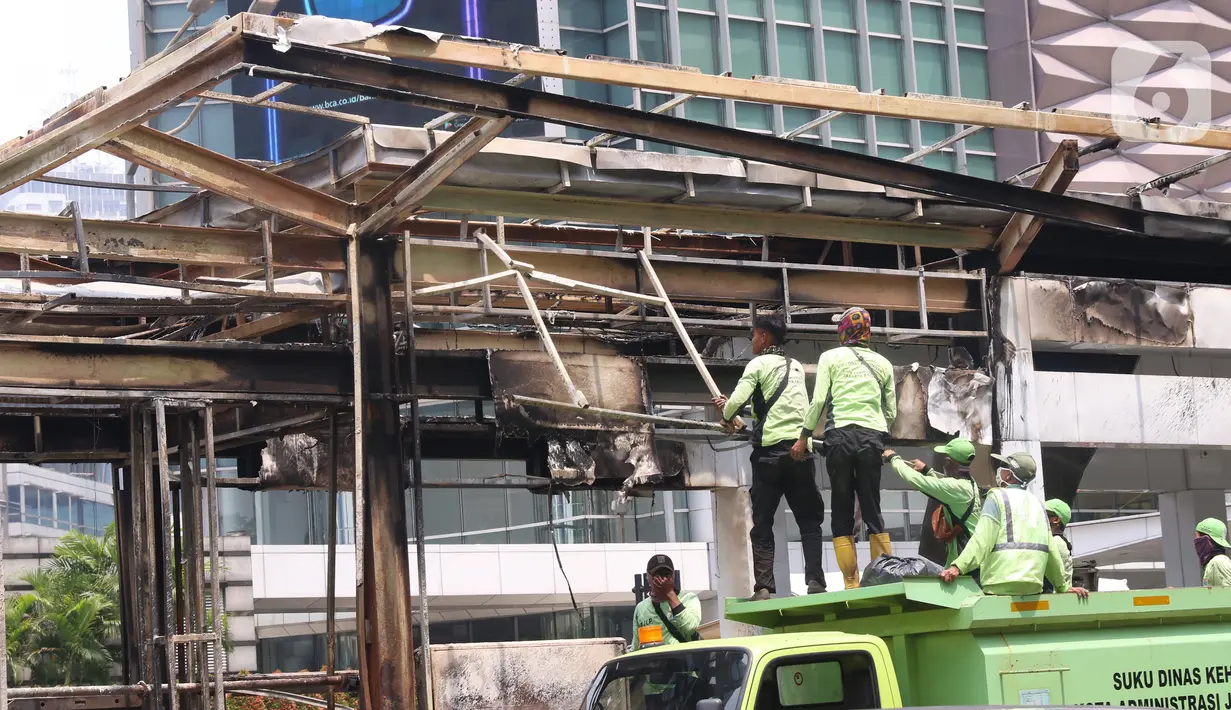 Sejumlah petugas membersihkan sisa kerusakan Halte Bus TransJakarta Tosari, Jakarta, Jumat (9/10/2020). Sejumlah fasilitas umum rusak dalam kericuhan unjuk rasa menolak pengesahan UU Cipta Kerja yang terjadi Kamis (8/10).  (Liputan6.com/Angga Yuniar)
