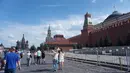 Sejumlah warga melintas di Red Square dengan tampak kanan Mauseleum Lenin dan belakang Saint Basil Cathedral. (Bola.com/Okie Prabhowo)