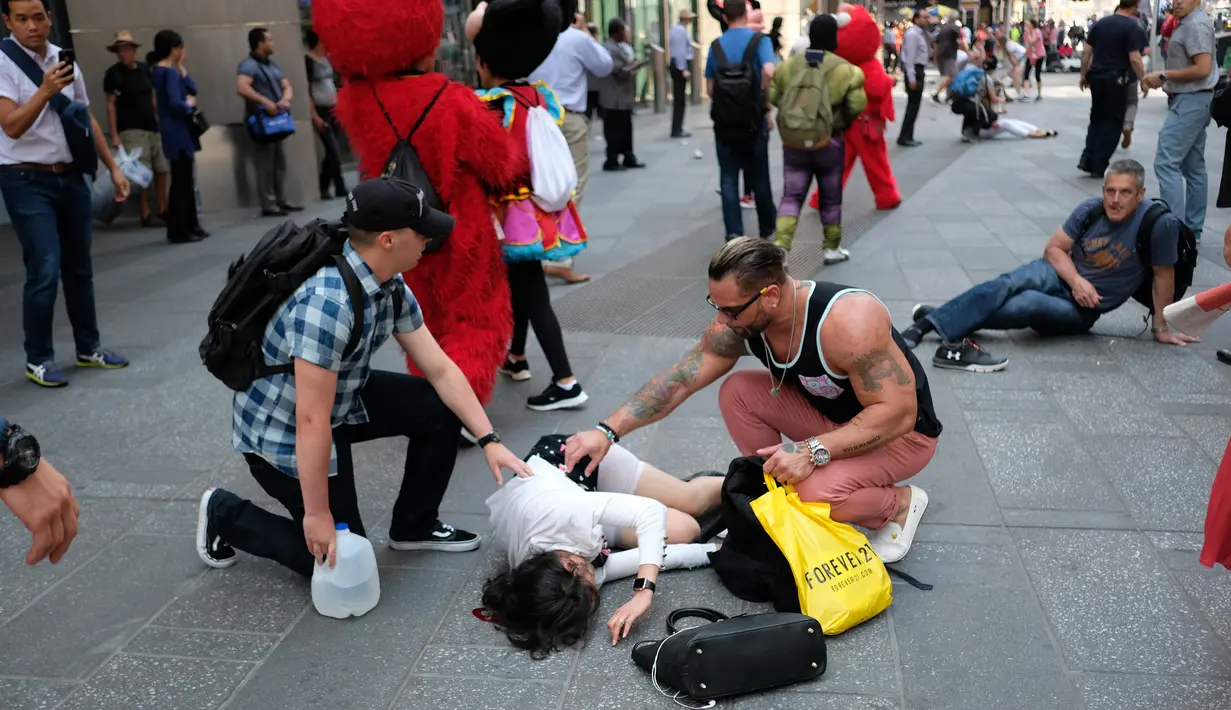 Sejumlah orang menghampiri korban terluka setelah sebuah mobil melaju kencang ke arah pejalan kaki di trotoar Times Square, New York, Kamis (18/5). Pihak berwenang menyebut tidak ada indikasi tindakan terorisme terkait kejadian itu. (Jewel SAMAD/AFP)