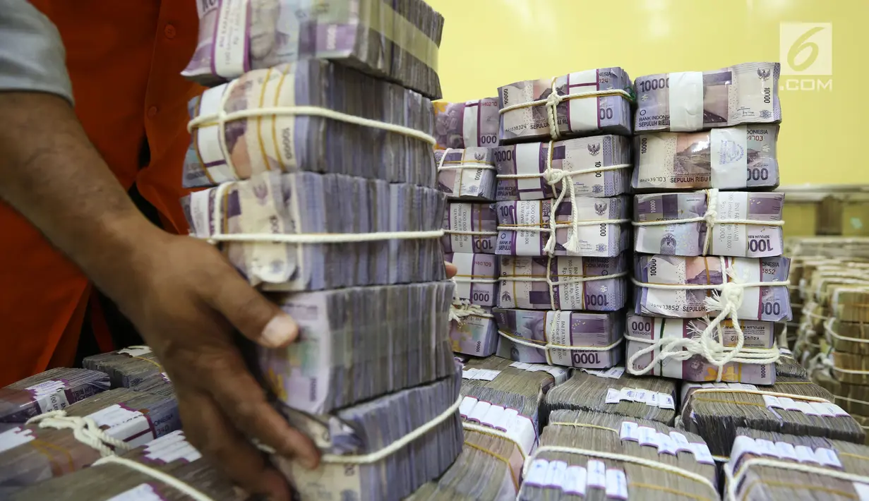Petugas menata tumpukan uang kertas di ruang penyimpanan uang "cash center" BNI, Jakarta, Kamis (6/7). Tren negatif mata uang Garuda berbanding terbalik dengan Indeks Harga Saham Gabungan (IHSG) yang mulai bangkit ke zona hijau (Liputan6.com/Angga Yuniar)