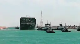 Kapal kargo Ever Given ditemani kapal tunda saat melaju di Terusan Suez, Mesir, Senin (29/3/2021). Ratusan kapal sedang menunggu untuk melewati kanal yang menghubungkan Mediterania ke Laut Merah. (Suez Canal Authority via AP)