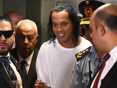 Mantan pemain timnas Brasil, Ronaldinho (tengah) tiba di Asuncion's Justice Palace, ibu kota Paraguay, Asuncion, Jumat (6/3/2020). Ronaldinho bersama saudara laki-lakinya berurusan dengan pihak berwenang Paraguay karena menggunakan paspor palsu untuk memasuki negara itu. (Norberto DUARTE/AFP)