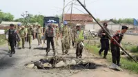 Satpol PP dan polisi membersihkan material batang bambu dan batu yang digunakan warga untuk memblokade jalan rusak akibat proyek tol Pemalang. (Foto: Liputan6.com/Polres Pemalang/Muhamad Ridlo)