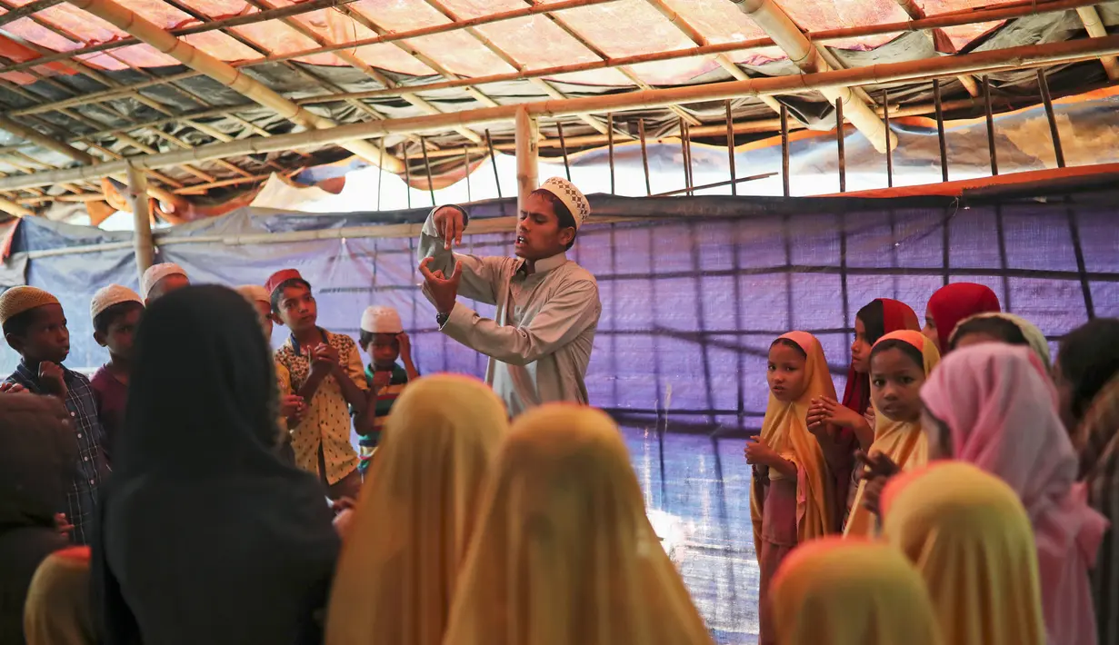Seorang guru mengajarkan bahasa Arab kepada anak-anak pengungsi Rohingya di kamp pengungsi di Cox's Bazar, Bangladesh (8/4). (Reuters/Mohammad Ponir Hossain)