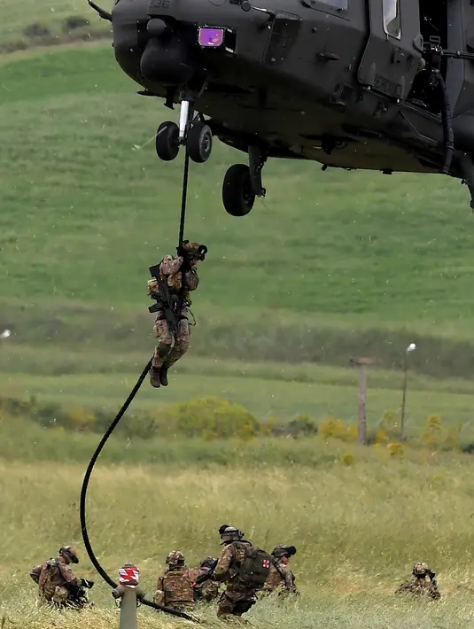Seorang tentara Italia turun dari helikopter saat ikut ambil bagian dalam latihan militer di sebuah kamp pelatihan di Tarquinia, dekat Roma, (21/5).  (AFP Photo/Tiziana Fabi)