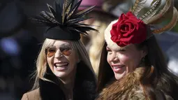 Dua wanita tersenyum saat tiba untuk hari pertama Festival Cheltenham di Cheltenham Racecourse, Inggris, Selasa (15/3/2022). Cheltenham adalah pertemuan berbasis pacuan kuda dalam kalender balap Perburuan Nasional di Inggris Raya. (Mike Egerton/PA via AP)