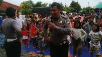 Sejumlah personel Polrestabes Surabaya menghibur puluhan anak dari eks anggota Gafatar. (Liputan6.com/Dian Kurniawan)