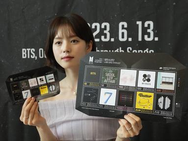 Seorang model memperlihatkan selembar prangko menandai peringatan 10 tahun debut band K-Pop BTS di sebuah kantor pos di Seoul, Korea Selatan, Senin (12/6/2023). Kantor pos mulai menjual prangko tersebut pada Selasa (13/6). (AP Photo/Ahn Young-joon)