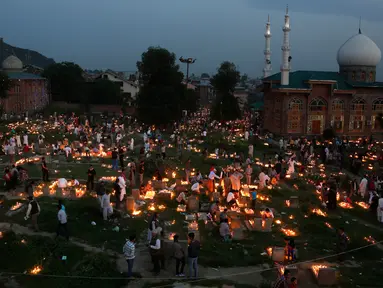 Sejumlah warga Kashmir menyalakan lilin di pemakaman keluarga dan saudara mereka saat memperingati Shab-e-Barat di pinggiran Srinagar, Kashmir (11/5). Selain itu mereka juga berdoa untuk sanak keluarga mereka. (AP Photo / Mukhtar Khan)