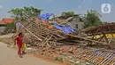 Anak-anak melintasi puing-puing bangunan rumah yang rusak diterjang angin puting beliung di Kaliabang Tengah, Kota Bekasi, Sabtu (24/10/2020). Menurut Badan Penanggulangan Bencana Daerah (BPBD) sebanyak 159 rumah terdampak puting beliung yang terjadi Jumat siang. (Liputan6.com/Herman Zakharia)