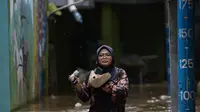 Warga melintasi banjir di kawasan Kebon Pala, Kampung Melayu, Jakarta Timur, Sabtu (16/7/2022). Meskipun ketinggian air sudah mencapai paha orang dewasa, warga setempat belum memutuskan untuk mengungsi. (merdeka.com/Imam Buhori)