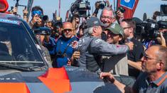 Pembalap Team Audi Sport, Carlos Sainz (tengah kiri) mendapatkan pelukan dari sang anak, yang juga seorang pembalap Formula 1, Carlos Sainz Jr saat memenangkan Reli Dakar 2024 setelah menyelesaikan etape terakhir di Yanbu, Arab Saudi, Jumat, 19 Januari 2024 waktu setempat. (AFP/Patrick Hertzog)