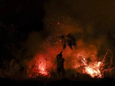 Seorang pria mencoba memadamkan api dengan dahan pohon di Trancoso, Portugal, pada 12 Agustus 2025. (PATRICIA DE MELO MOREIRA/AFP)